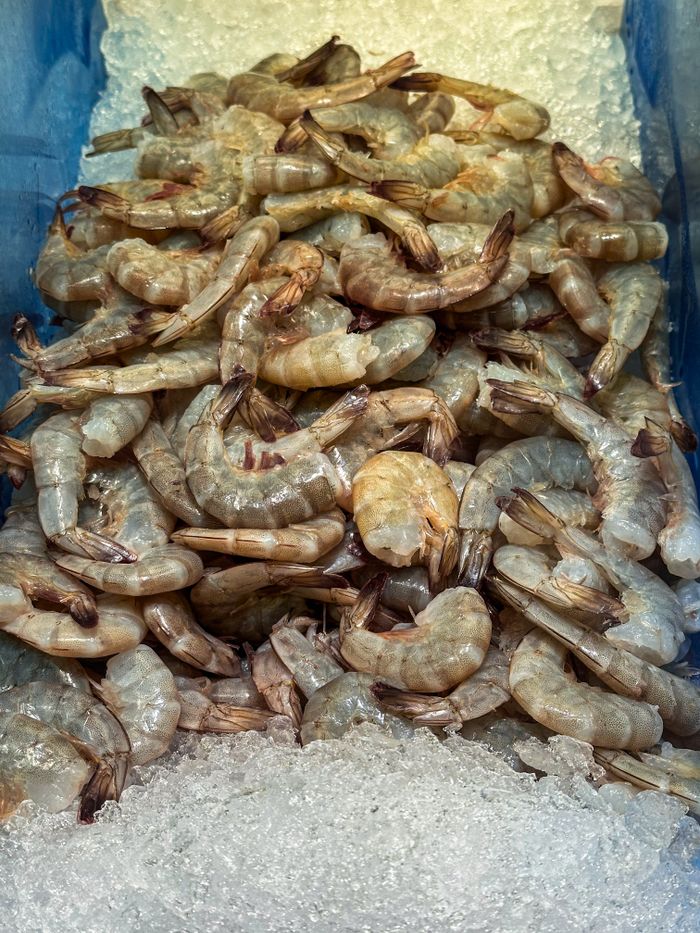 A pile of raw shrimp displayed on ice in a seafood market setting.